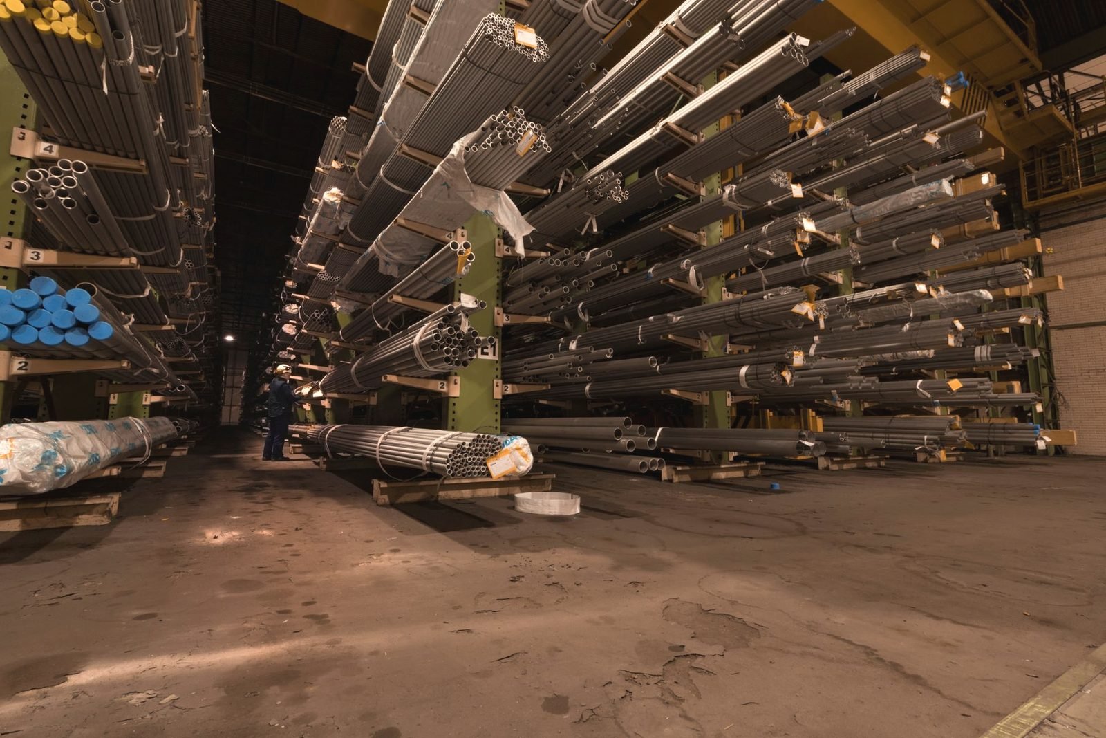 Long aisle of steel pipe stored on tall racks inside a warehouse