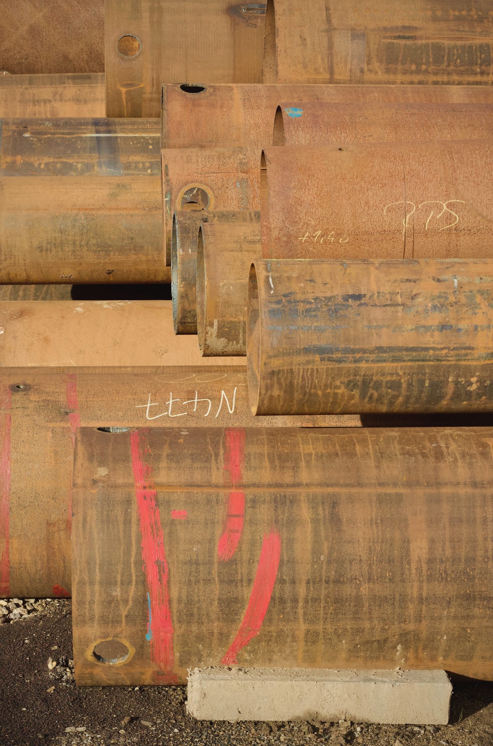 Stack of rusty steel pipe with paint marks on the ends